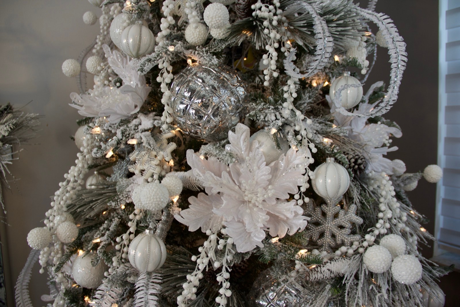White lace flowers and mercury glass on the flocked branch.