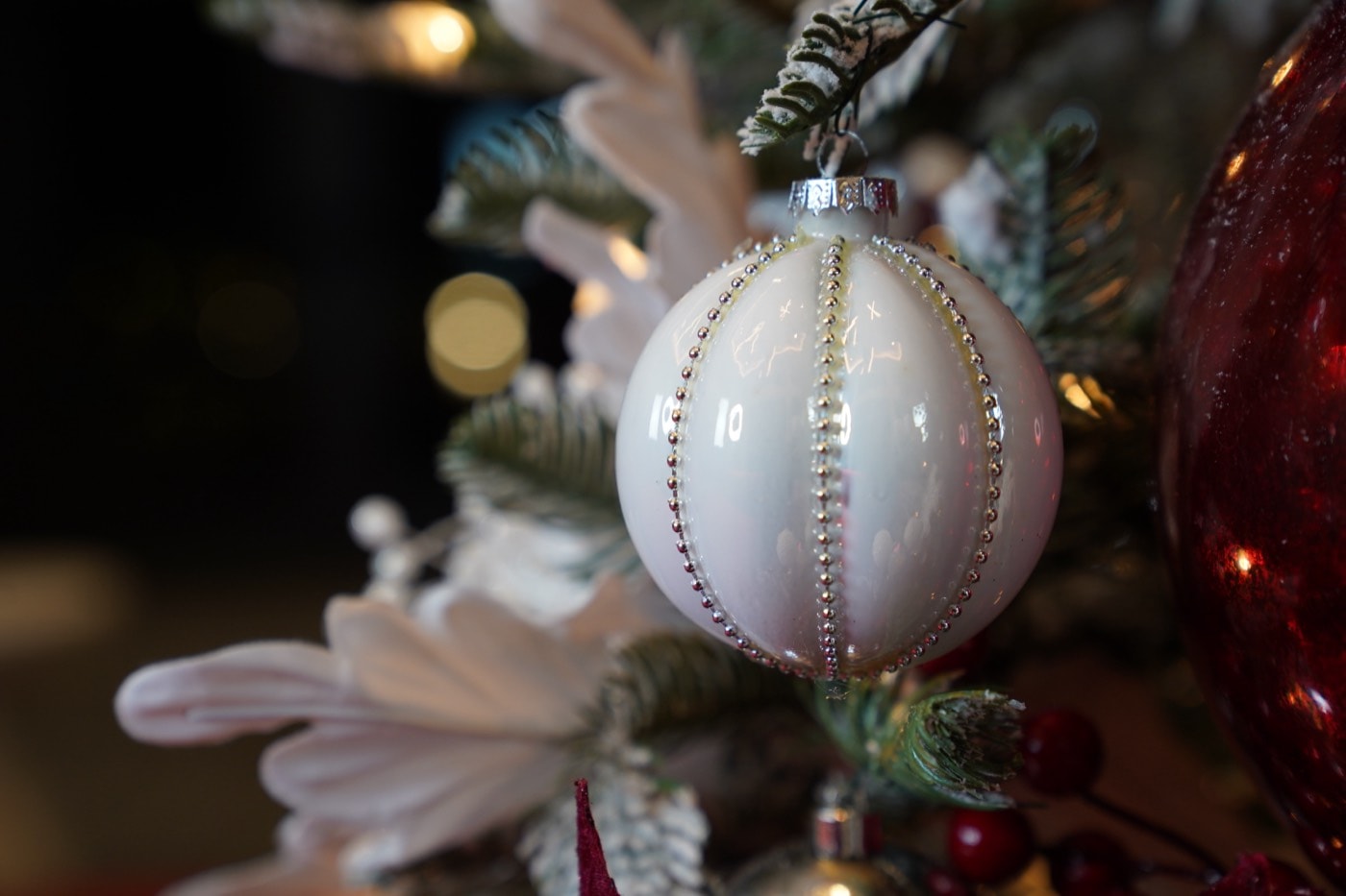 A white glass sphere, segmented by rows of silver pearls.