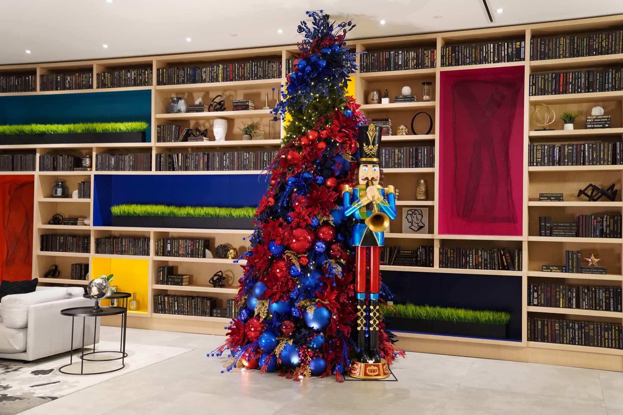 The Johan Nova nutcracker beside a red and blue tree in a library